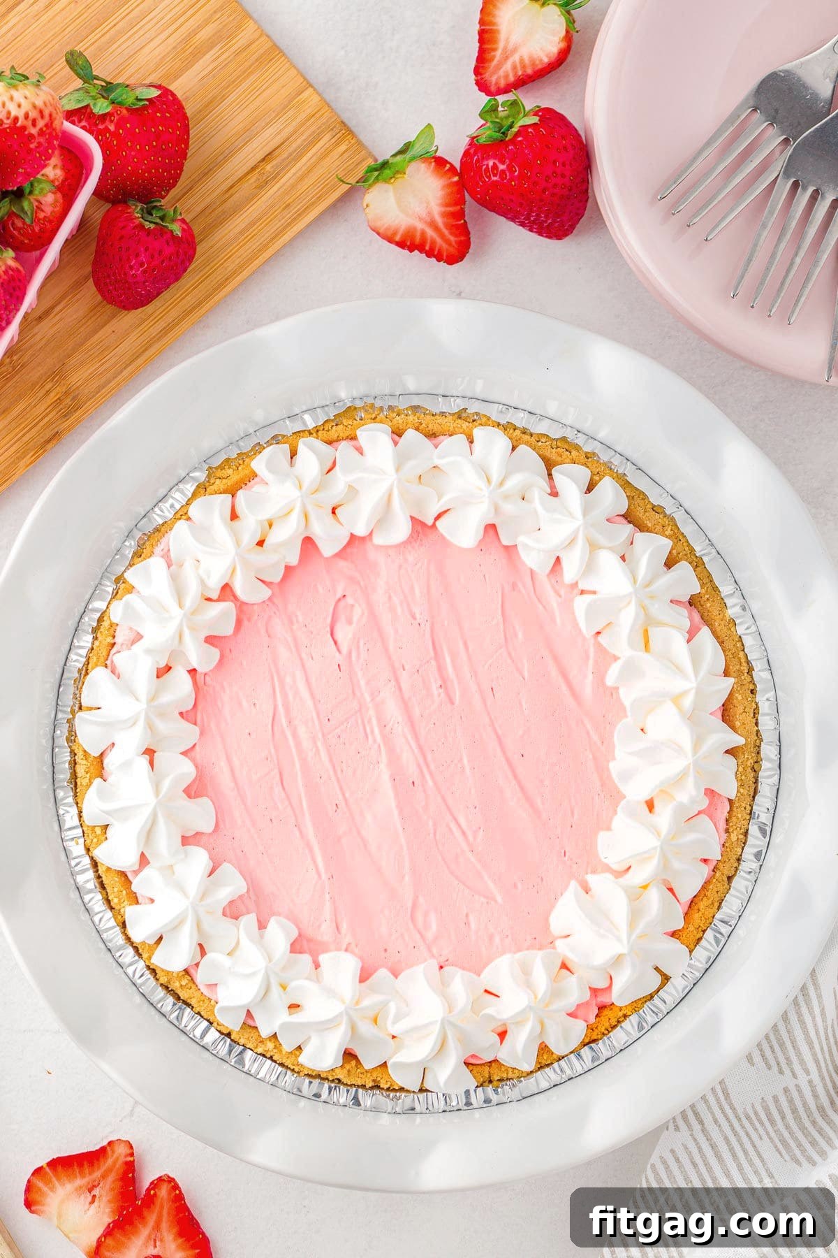 A top-down view of a colorful Kool Aid pie, perfectly chilled and adorned with generous swirls of whipped cream, resting on a clean white surface, inviting a delicious spoonful.