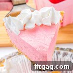 Piece of kool aid pie topped with whipped cream being held up over the rest of the pie.