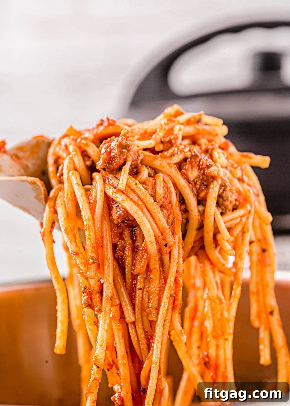 One Pot Instant Pot Spaghetti 3 A serving spoon lifts a generous scoop of Instant Pot Spaghetti, showcasing the perfectly mixed meat sauce and tender noodles, just moments after cooking in the pressure cooker.