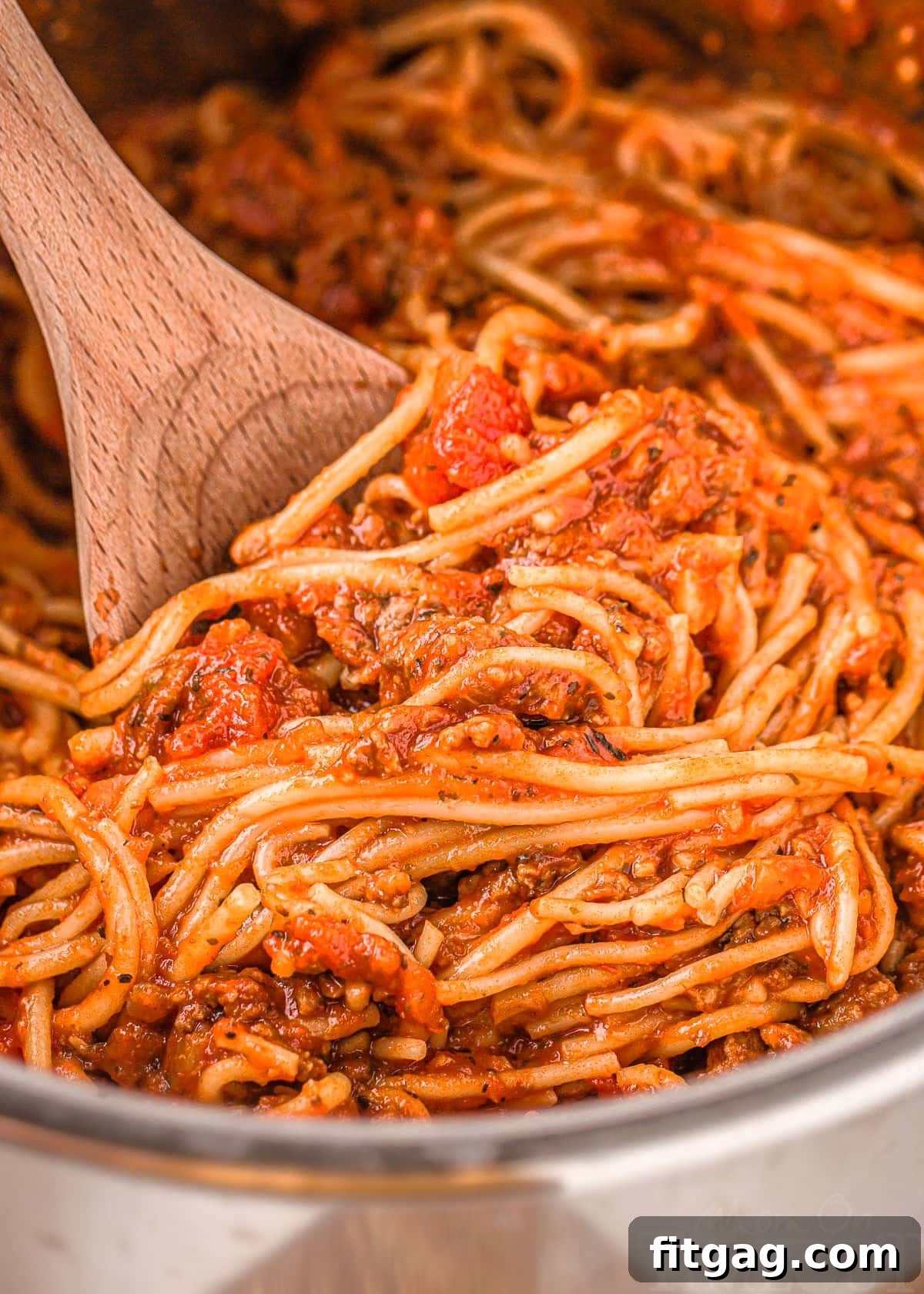 One Pot Instant Pot Spaghetti 7 A close-up shot of the Instant Pot's interior, showing a serving of freshly cooked spaghetti with meat sauce, ready to be scooped out with a wooden spoon for a hearty family dinner.