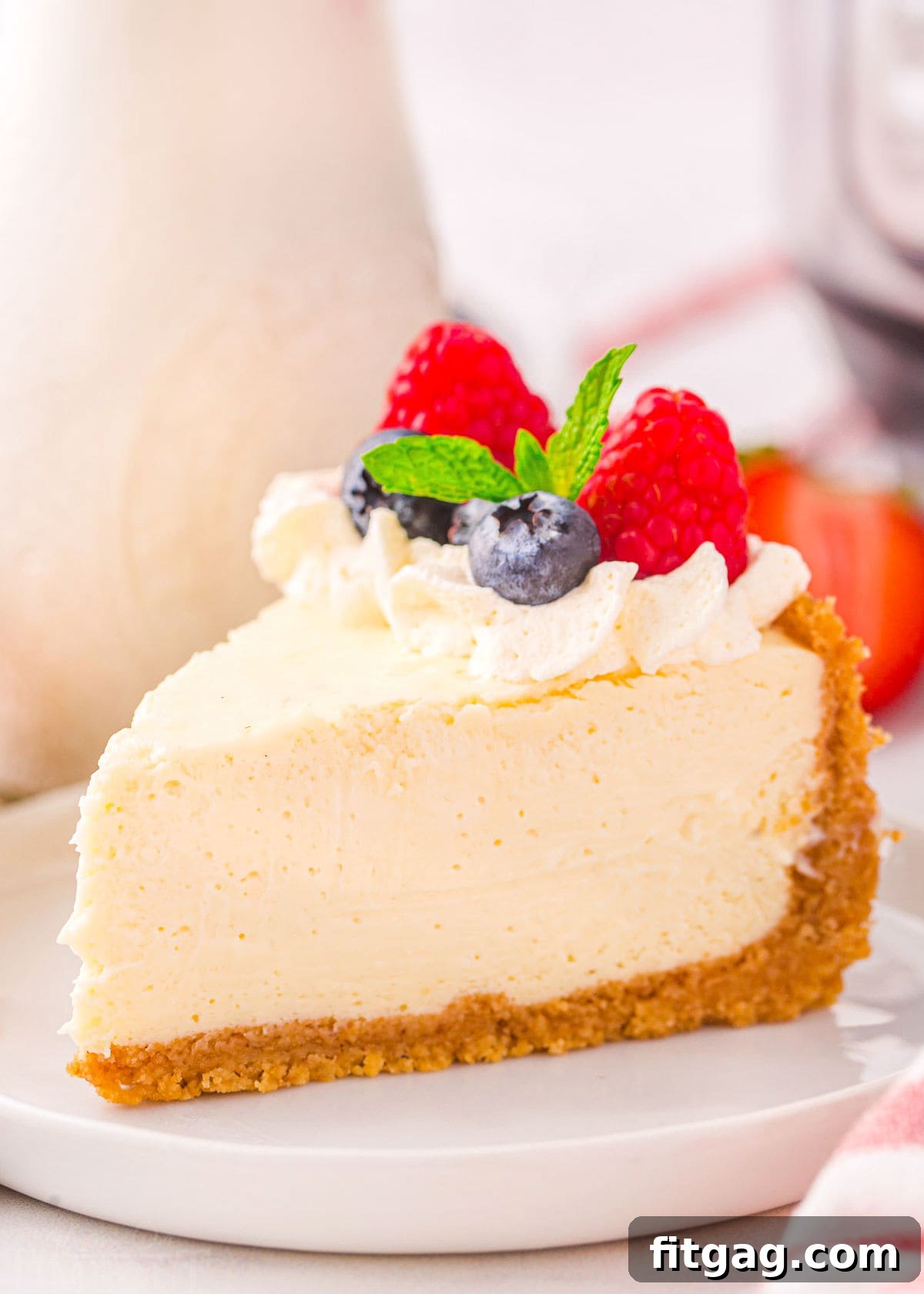 slice of cheesecake on white plate topped with whipped cream and berries.