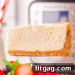 one slice of instant pot cheesecake being held above the rest of the cheesecake in front of an instant pot.