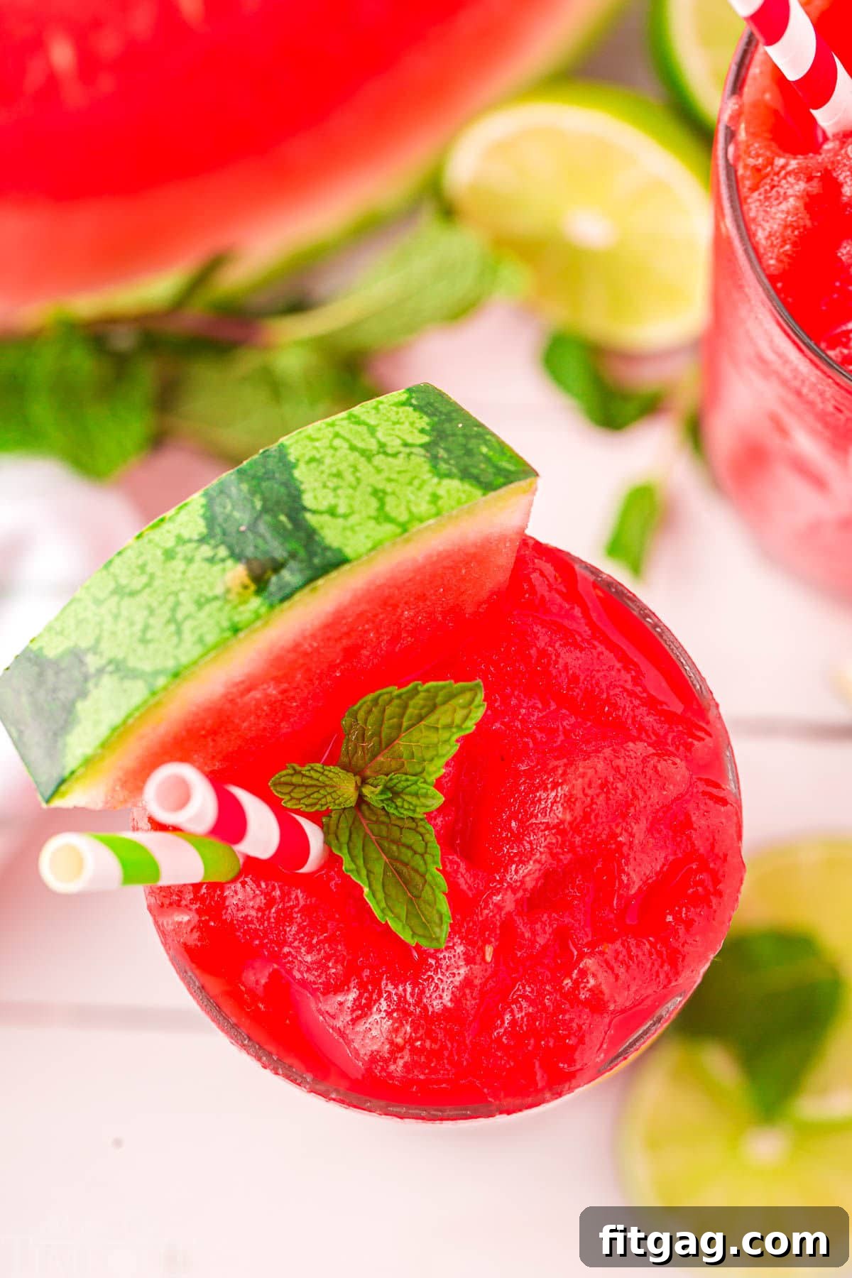 Top-down view of a watermelon slushie in a glass, with a half watermelon beside it, creating a vibrant summer scene.