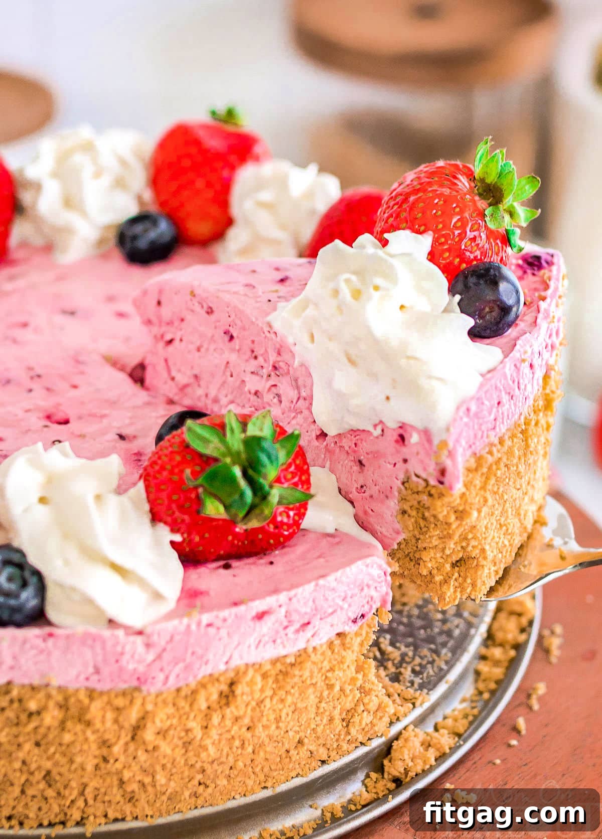 A perfect slice of berry cheesecake, revealing its creamy layers and graham cracker crust, being carefully lifted away from the main cheesecake.
