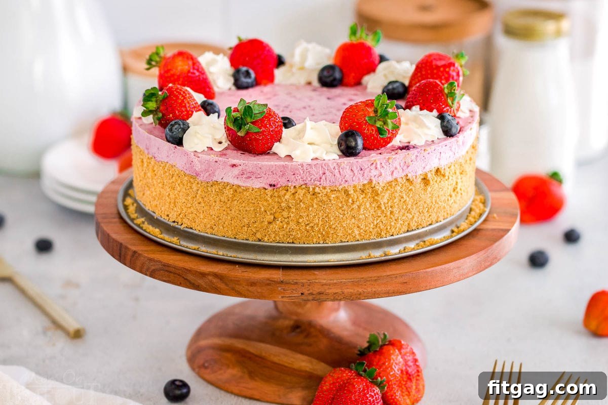 A wide, appetizing shot of a No Bake Berry Cheesecake, showcasing its vibrant berry and whipped cream topping, and a perfectly golden brown graham cracker crust, set on a rustic wooden cake stand.