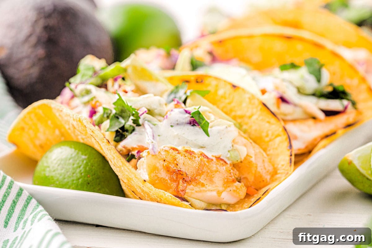 A fully assembled fish taco, beautifully plated with all its delicious toppings, including vibrant cabbage, a generous drizzle of creamy fish taco sauce, fresh avocado, and a sprinkle of cilantro.