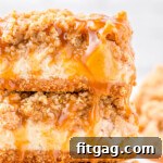Two caramel apple cheesecake bars stacked on a white plate with a gold rim. Caramel sauce is drizzled on top of the bars.