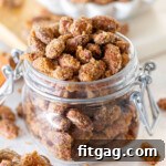 candied almonds in a glass jar filled to overflowing. a small white bowl of candied almonds can be seen in the background.