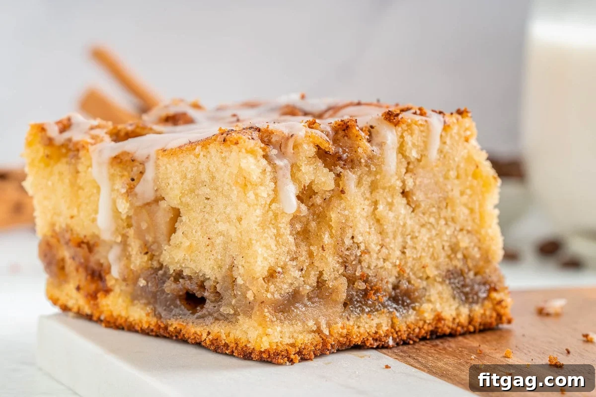 Autumn Apple Coffee Delight 4 one piece of apple coffee cake sitting on a marble and wood cutting board. coffee cake has a little glaze drizzled over the top.