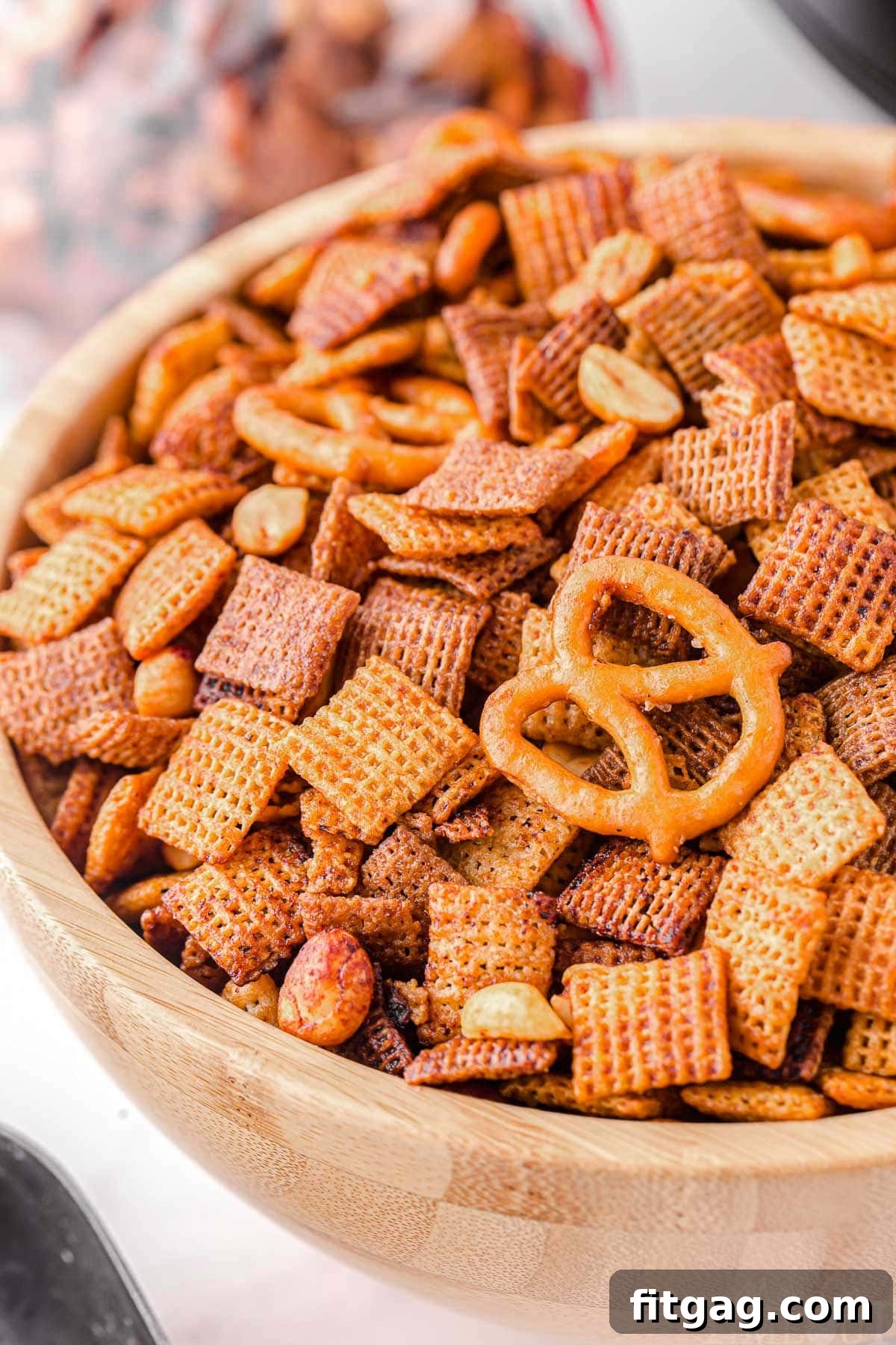 Slow Cooker Chex Mix Perfection 2 Close-up view of golden brown Crockpot Chex Mix in a large rustic wooden bowl, showcasing its crispy texture and savory coating. Perfect for game day snacks.