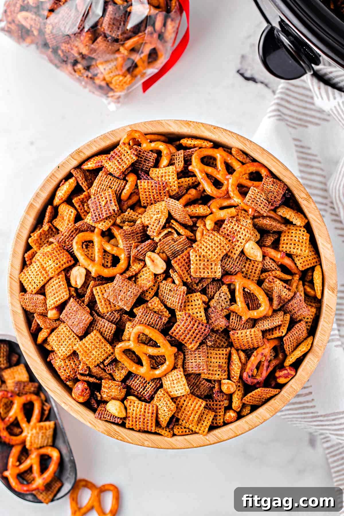 Slow Cooker Chex Mix Perfection 5 Top-down view of a generous serving of crispy Crockpot Chex Mix in a large wooden bowl, highlighting the vibrant colors and diverse textures of the savory snack.