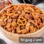 wood bowl in front of black slow cooker filled with chex mix.
