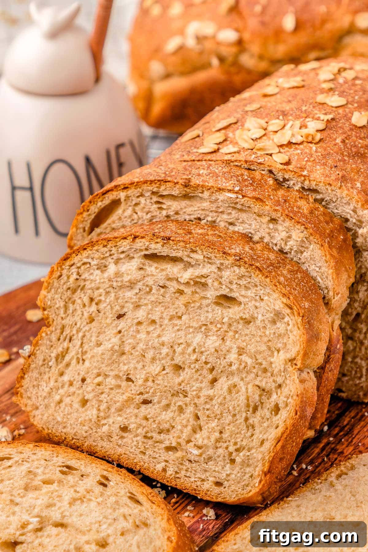 Wholesome Wheat Loaf 6 Two generous slices of warm, honey wheat bread, revealing their soft, open crumb, arranged on a rustic wooden board next to a jar of golden honey.