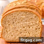 A freshly baked loaf of golden-brown whole wheat bread on a rustic wooden board, with a slice cut off, revealing its fluffy interior. Perfect for sandwiches, soups, and toast.
