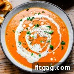 A steaming bowl of Instant Pot Tomato Soup, drizzled with heavy cream and garnished with fresh chopped basil.