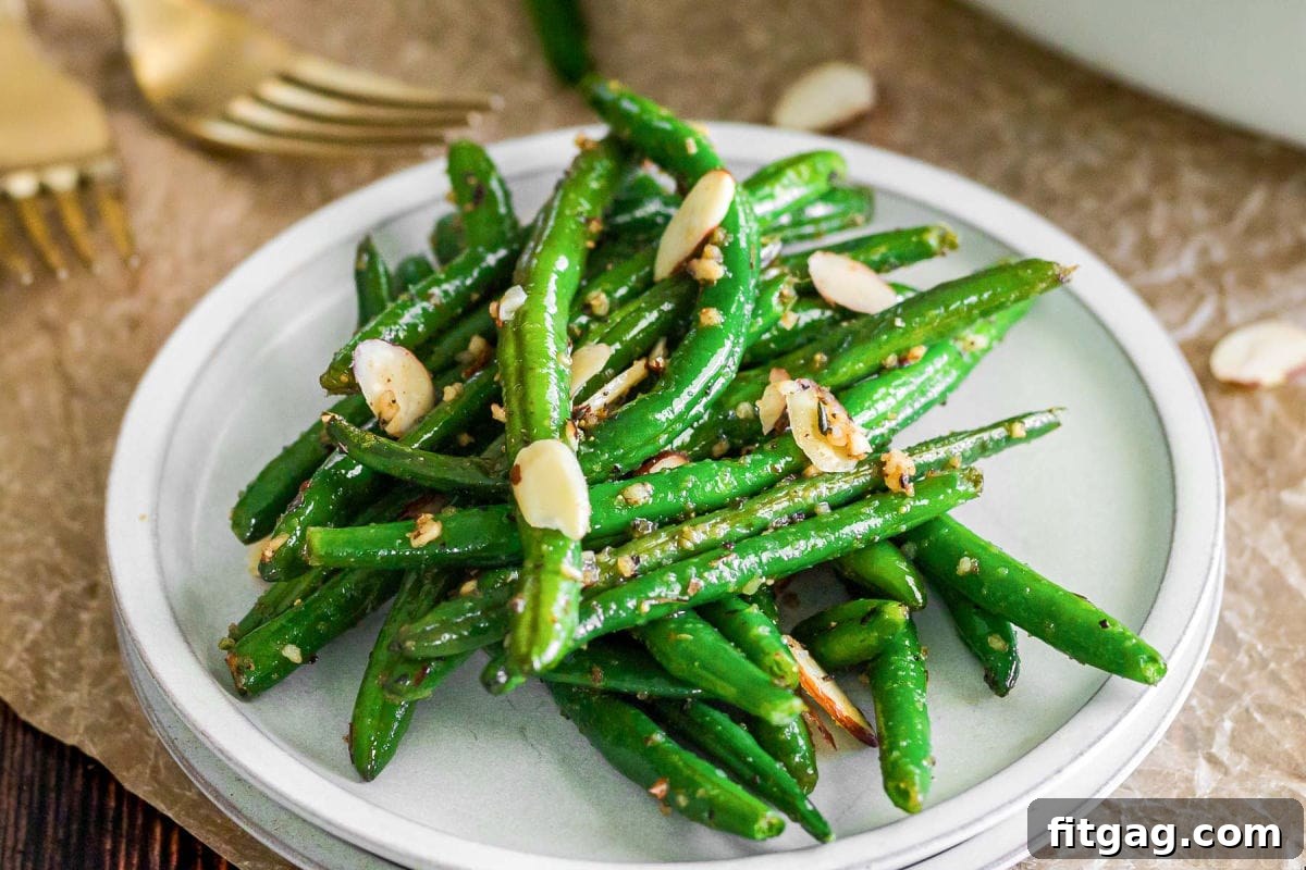 Small round white plate with a serving of garlic green beans, perfectly plated for a meal.
