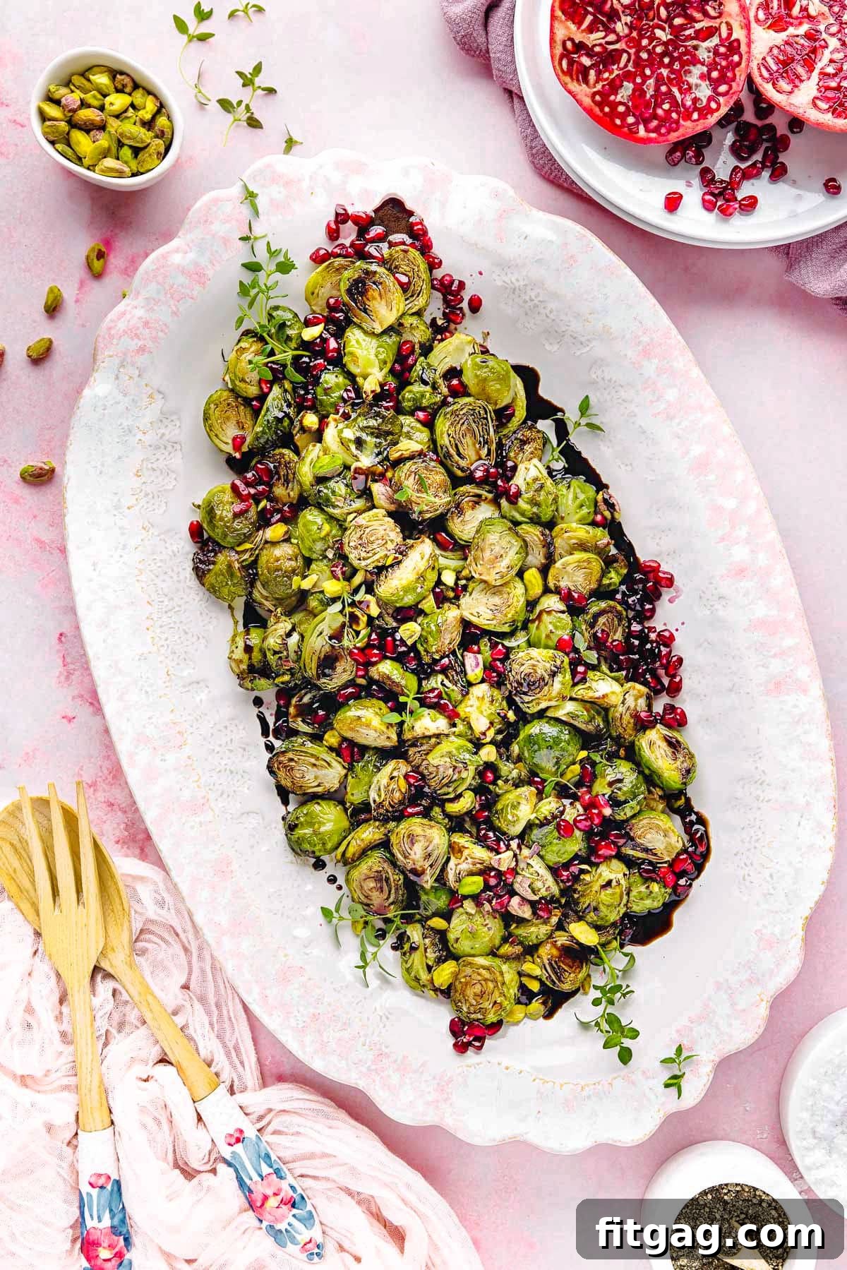 Caramelized Roasted Brussels Sprouts 3 top down view of roasted brussels sprouts on a large white and pink platter. Pomegranate seeds and pistachios garnish the gorgeous dish.