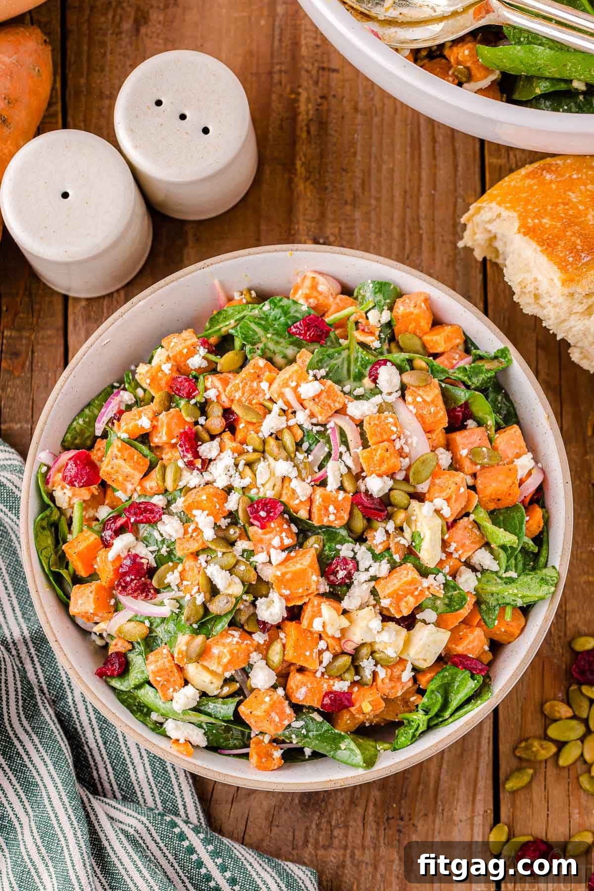 A vibrant Sweet Potato Salad in a large serving bowl, garnished with dried cranberries and pepitas for a beautiful presentation.