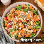 top down view of sweet potato salad in large serving bowl topped with dried cranberries and pepitas.