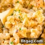 Liquid Gold Mac 7 close up look at velveeta mac and cheese recipe in baking dish with gold spoon scooping it out of the dish.
