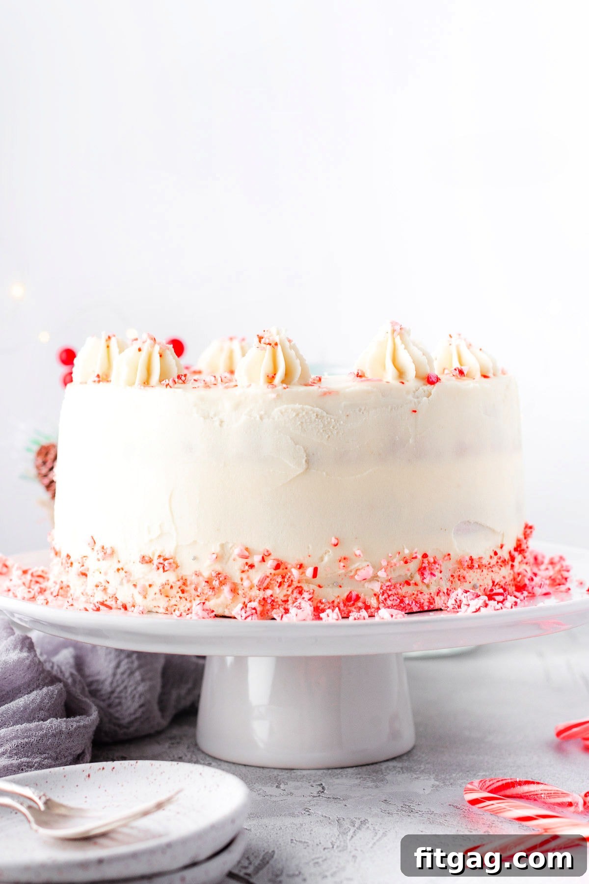 Frosted Peppermint Indulgence 2 A stunning whole Peppermint Cake on a pristine white cake stand, elegantly decorated with crushed candy canes scattered around its base, inviting you to celebrate the holidays.