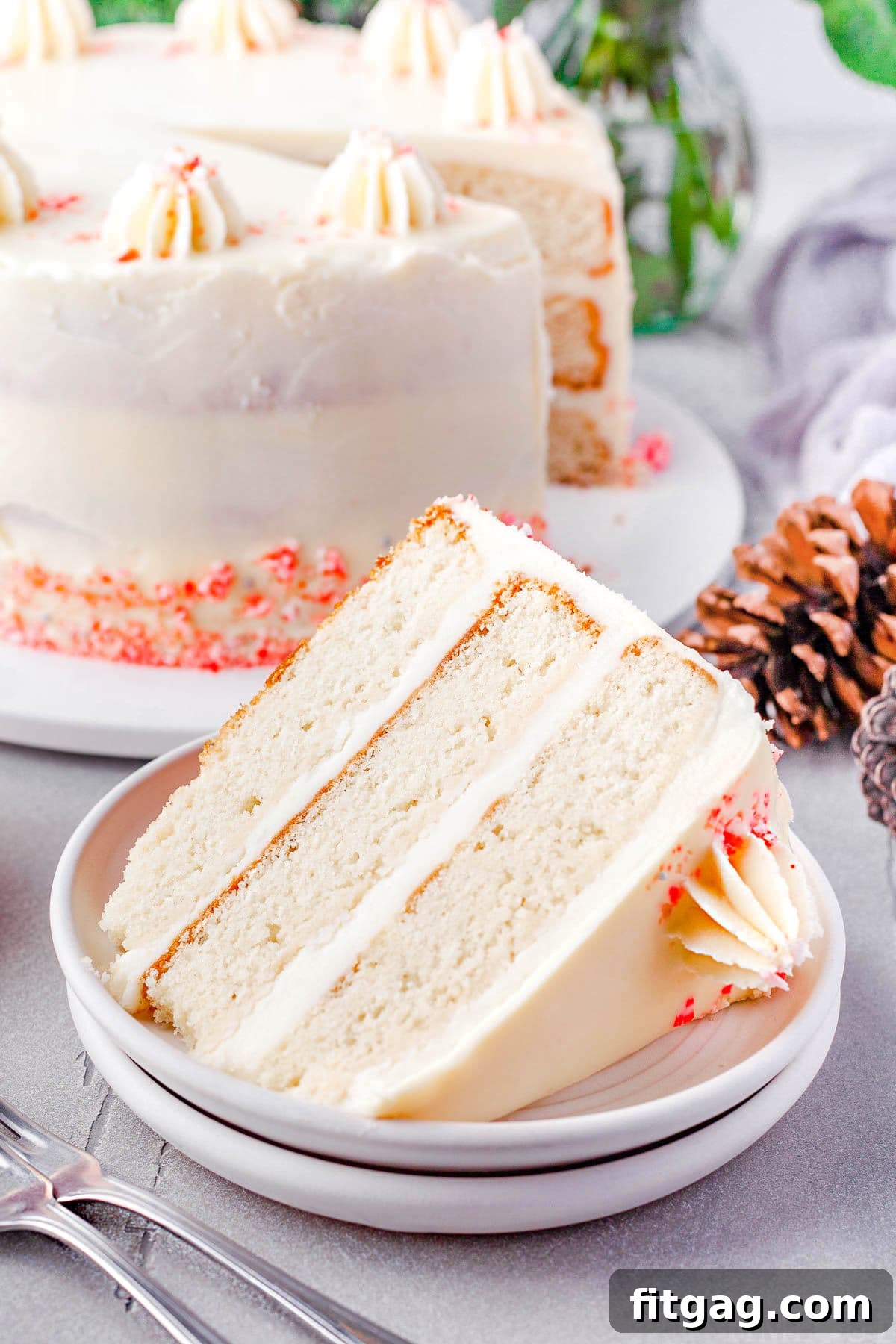 Frosted Peppermint Indulgence 3 A thick, inviting slice of Peppermint Cake sits on a white plate, showcasing its moist layers and creamy peppermint frosting, with the rest of the beautifully frosted cake visible in the soft background.