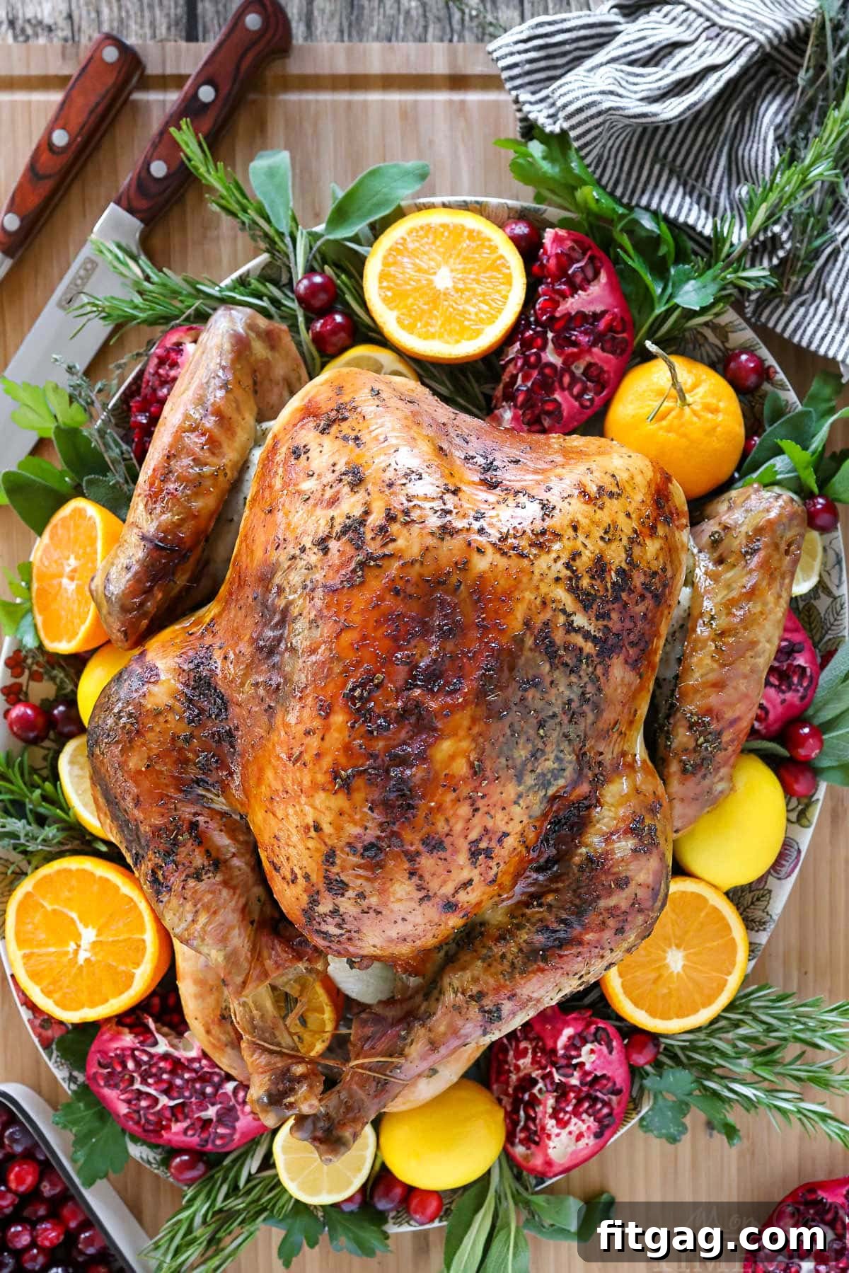 Unlock the Juiciest Thanksgiving Turkey 4 Top down view of the best thanksgiving turkey recipe on a serving platter with oranges, lemons, pomegranates, fresh herbs and cranberries.