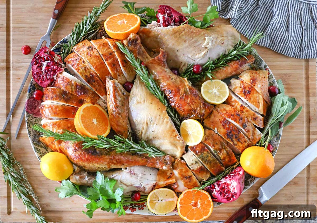 Unlock the Juiciest Thanksgiving Turkey 9 Top down view of Thanksgiving Turkey recipe plated on a large platter with fruit and herbs. Platter is sitting on a large cutting board.