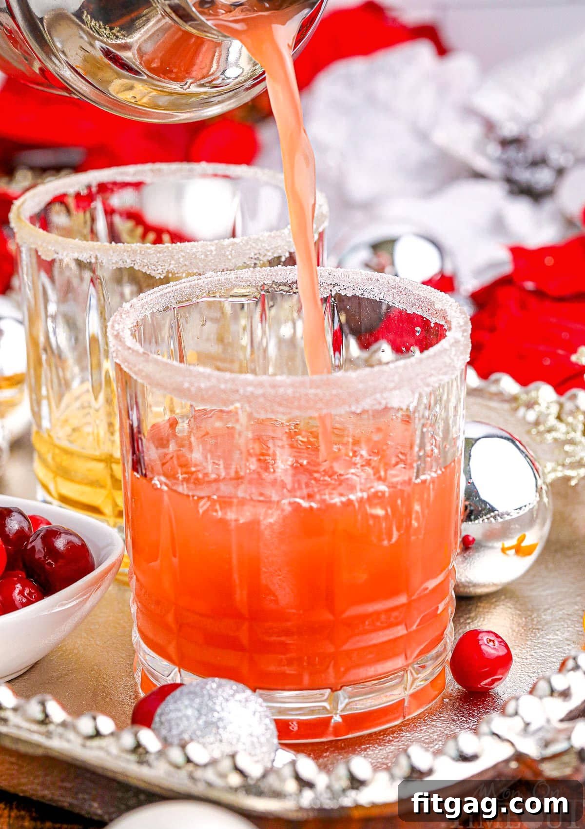 Holiday Spirit Sips 5 A festive Christmas cocktail being poured into a short crystal glass, resting on an elegant silver serving tray, ready for holiday enjoyment.