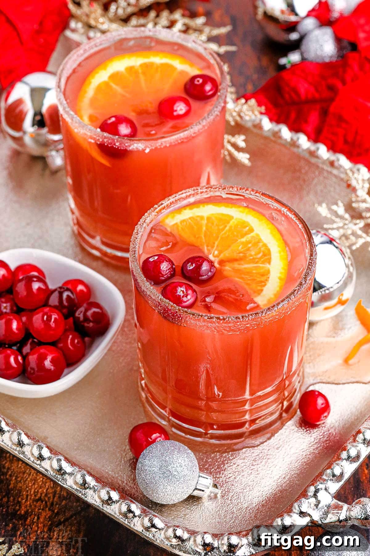 Holiday Spirit Sips 6 Two festive Cranberry Christmas Cocktails on a silver serving platter, beautifully garnished with fresh cranberries and orange slices, ready for a holiday toast.