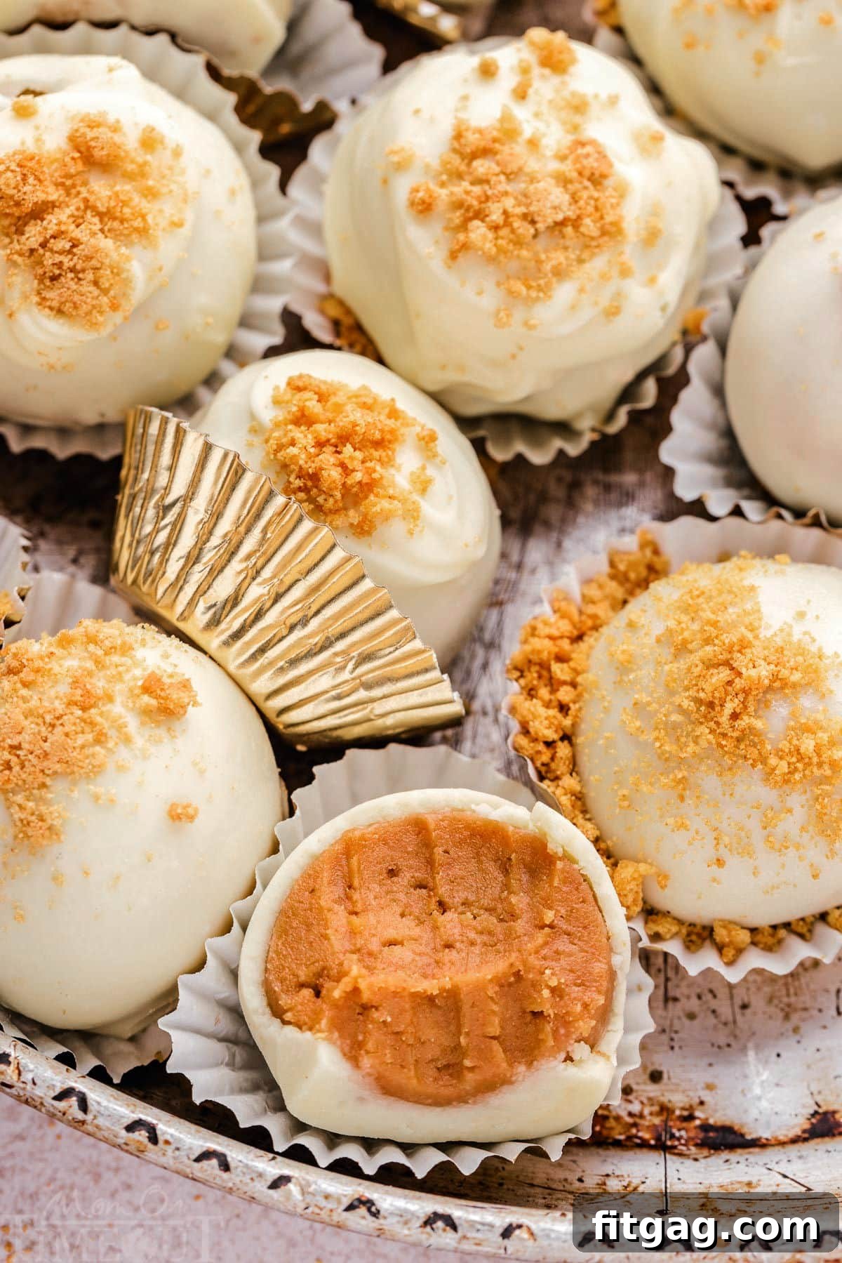 Ginger truffles elegantly arranged on a metal plate, nestled in gold liners. One truffle shows a tempting bite taken out of it.