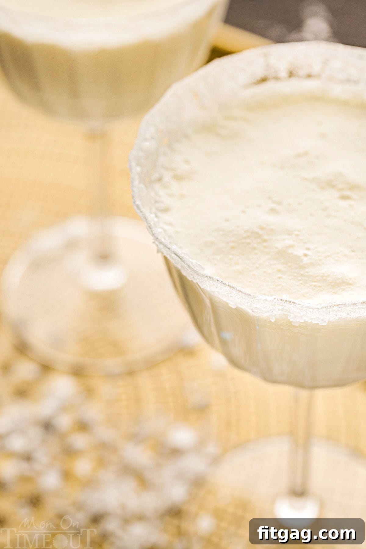An angled top-down view of a pristine white martini in a tall glass, beautifully dusted with sugar to evoke a snowy, wintery appearance, perfect for the holiday season.
