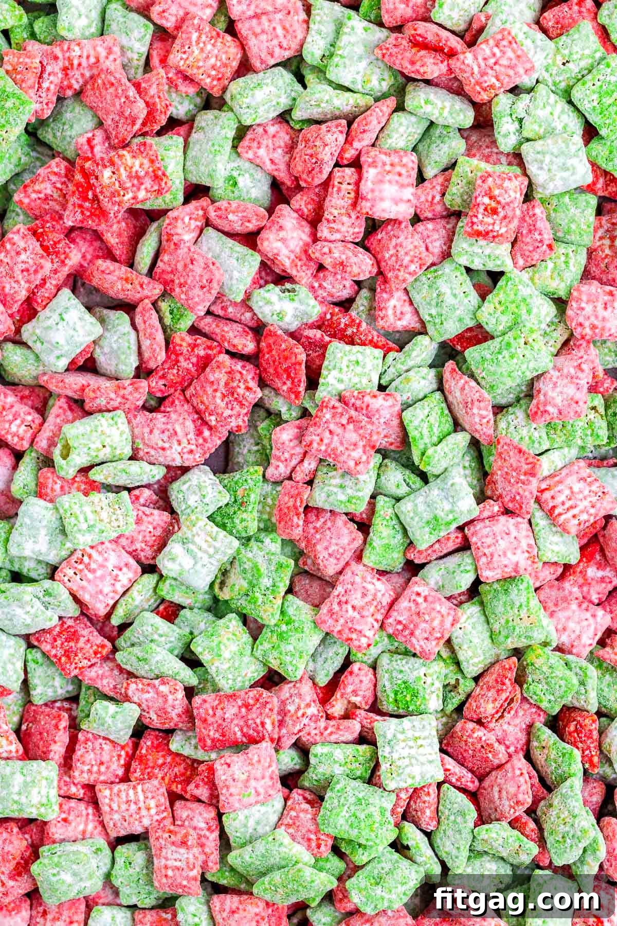 Holiday Crunch Mix 4 A close-up view of vibrant red and green muddy buddies, highlighting the powdered sugar coating and the distinct colors of the Christmas puppy chow.