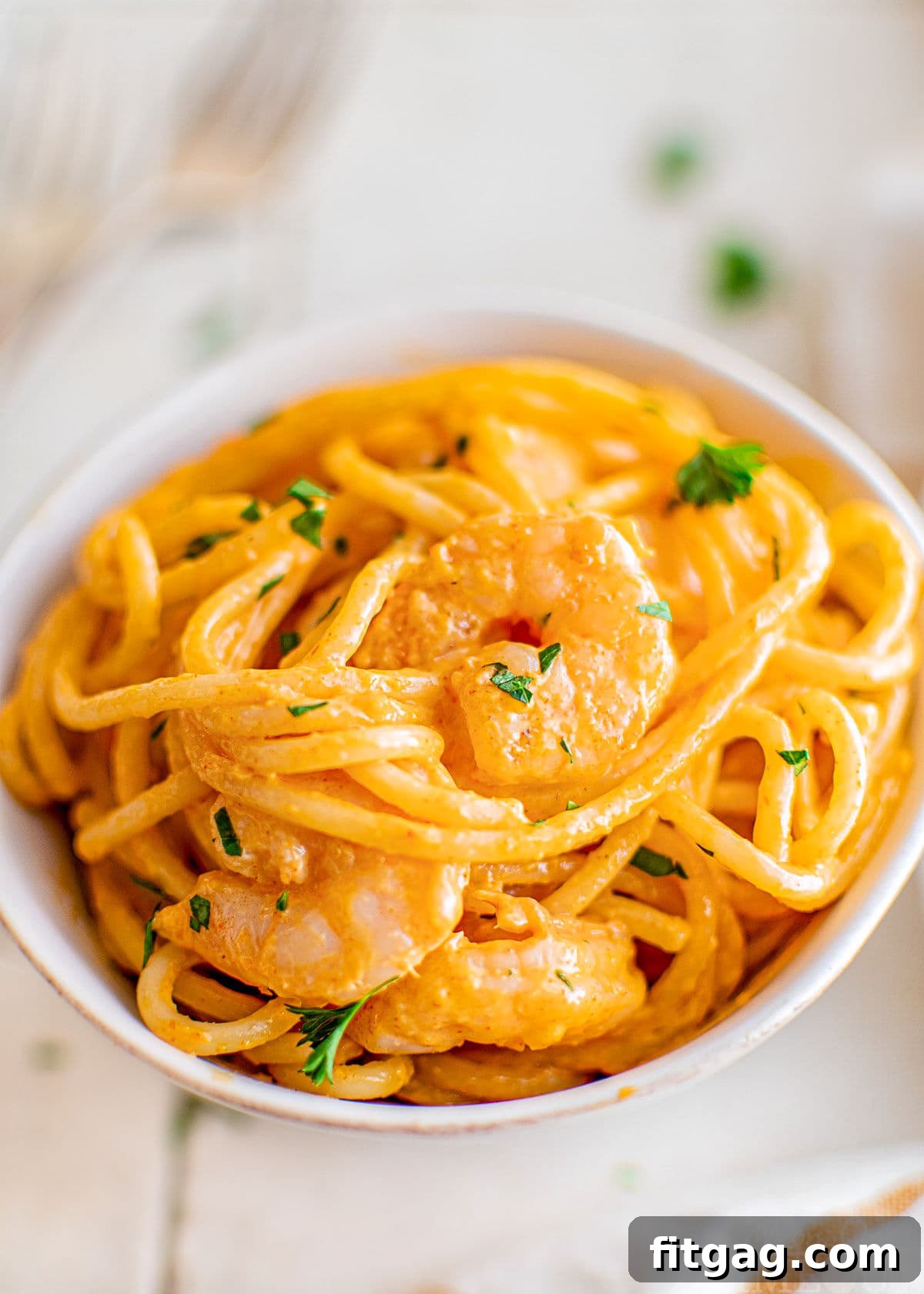 Creamy Bang Bang Shrimp Pasta 3 small bowl with bang bang shrimp pasta in it. the bowl is white and the pasta is garnished with fresh parsley.