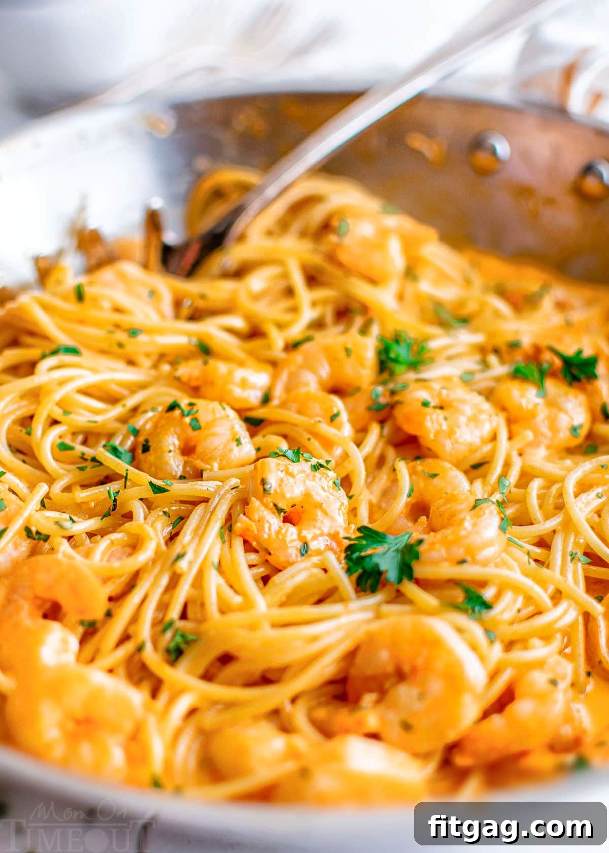 Creamy Bang Bang Shrimp Pasta 5 close up of bang bang shrimp pasta in a large stainless steel skillet topped with fresh parsley.