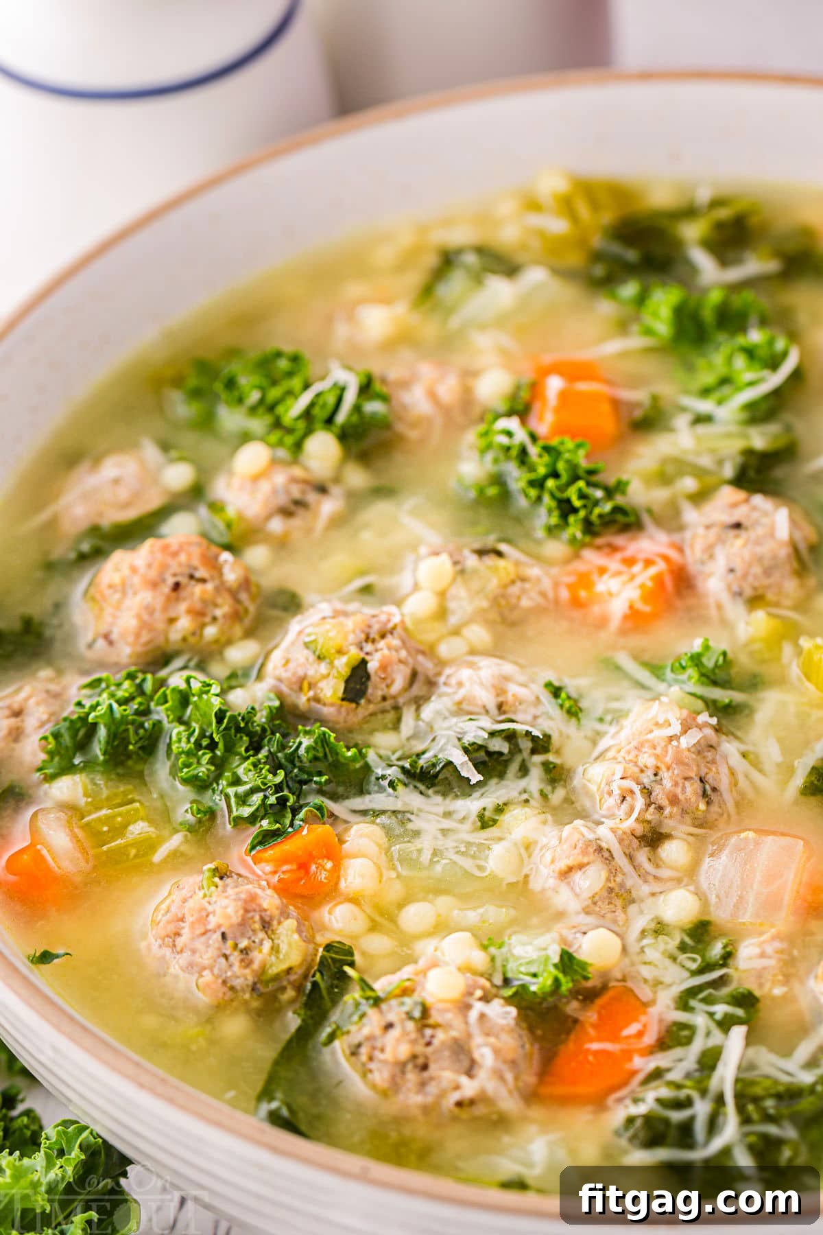 Italian Union Soup 6 close up look at italian wedding soup in a round bowl. the soup has been topped with Parmesan cheese.