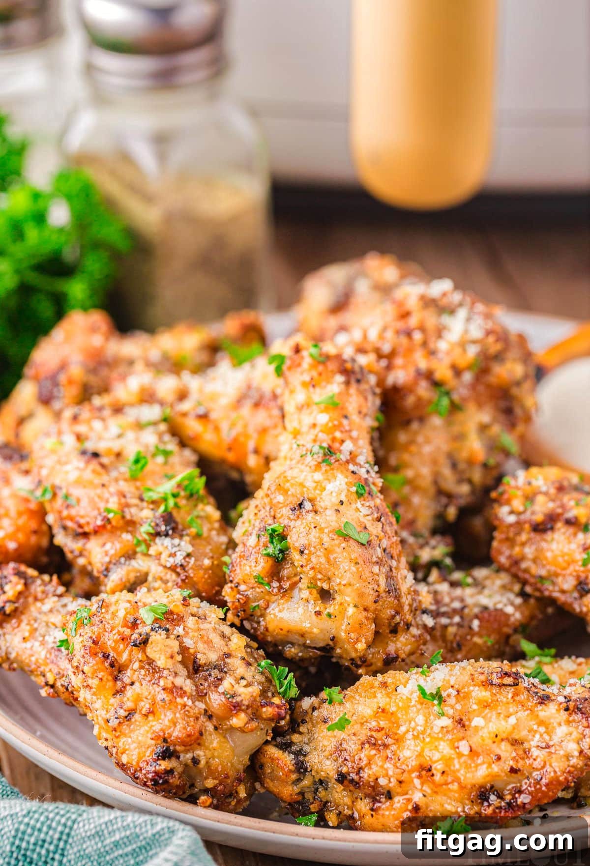 Crispy Garlic Parmesan Wings 2 A vibrant serving platter piled high with crispy golden garlic parmesan wings, generously garnished with fresh green parsley.