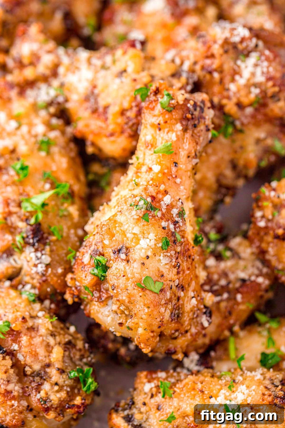 Crispy Garlic Parmesan Wings 6 A close-up view of freshly cooked garlic parmesan chicken wings, dusted with grated Parmesan cheese and finely chopped parsley, highlighting their delicious texture.