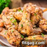 serving plate loaded with crispy golden garlic parmesan wings that have been garnished with fresh parsley.