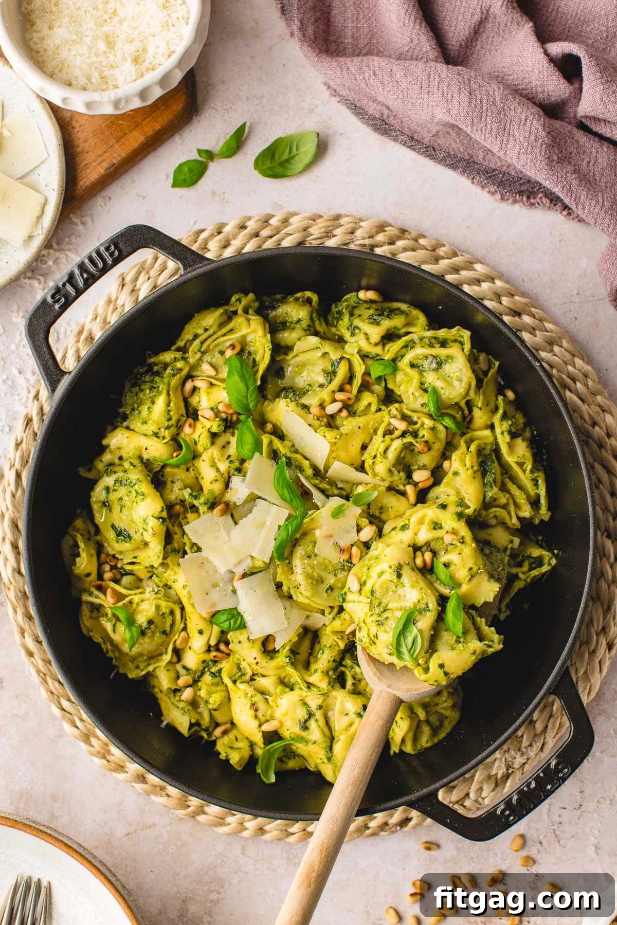 Creamy Pesto Tortellini Delight 2 top down look at pesto tortellini in a black cast iron skillet. made with fresh basil pesto and topped with Parmesan and basil.