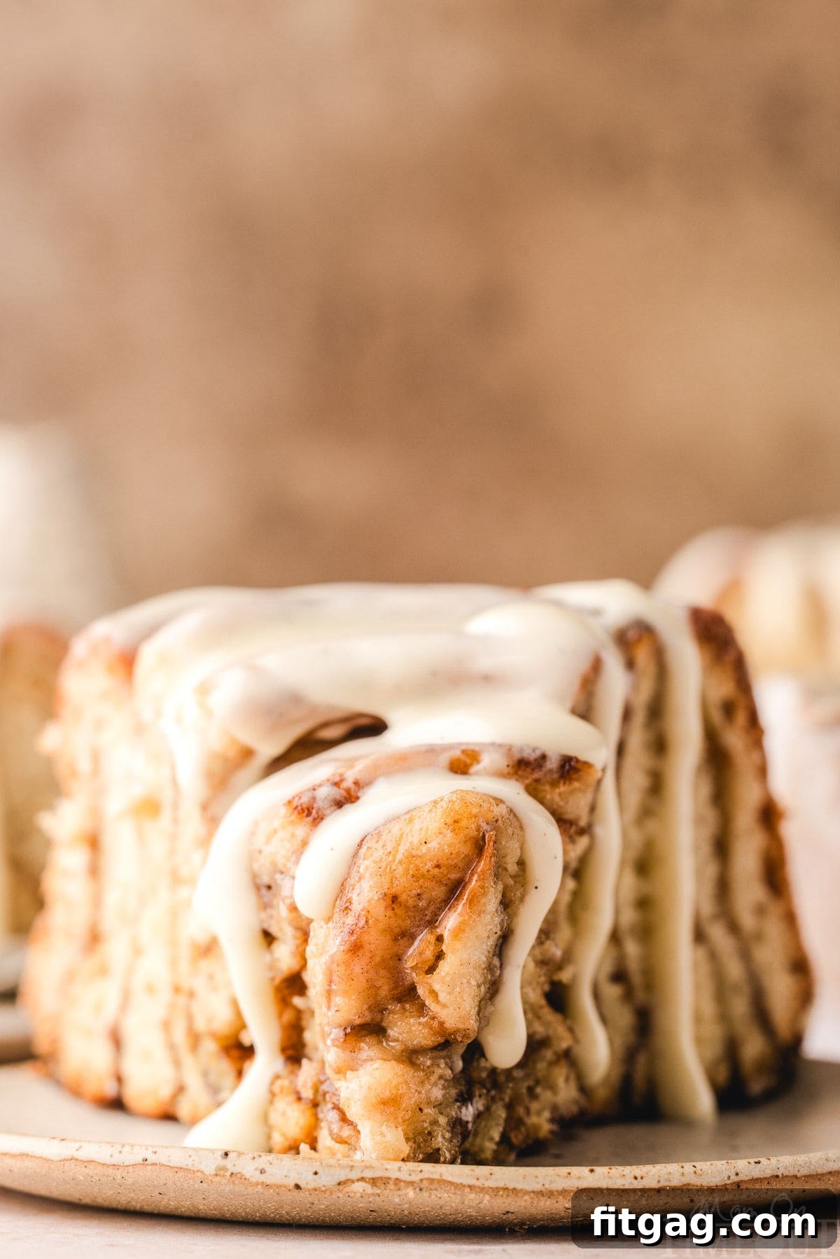 Colossal Cinnamon Swirl Cake 8 Slice of giant cinnamon roll cake recipe on small white plate. Cake has been drizzled with cream cheese glaze.