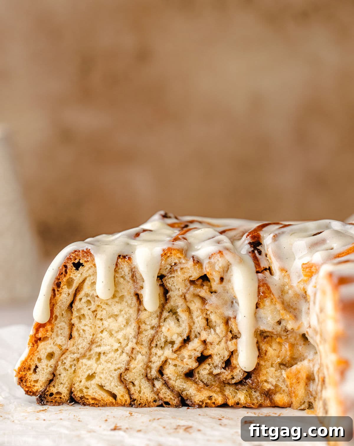 Colossal Cinnamon Swirl Cake 9 cross sectional view of the cinnamon roll cake showing all the swirls of cinnamon sugar filling with the glaze dripping down the sides of the cake.