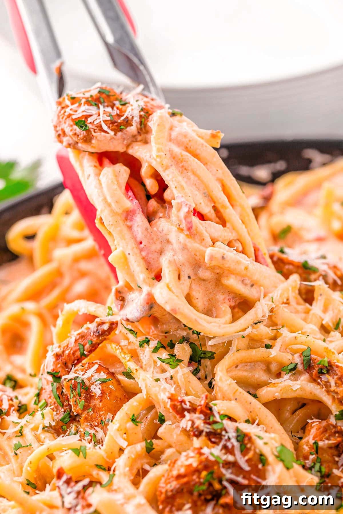 Tongs gracefully lifting a portion of creamy Cajun Shrimp Pasta directly from the skillet, ready to be served and enjoyed.