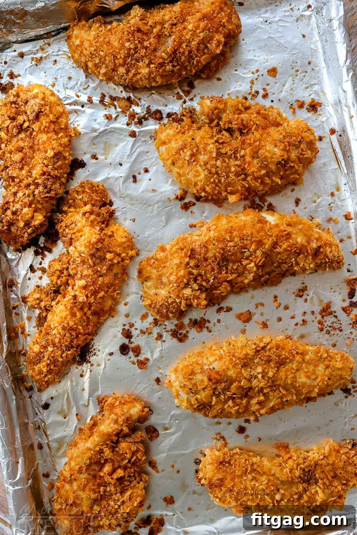 A top-down shot of perfectly cooked, golden-brown Cornflake Chicken strips arranged neatly on a baking sheet, showcasing their crispy texture.