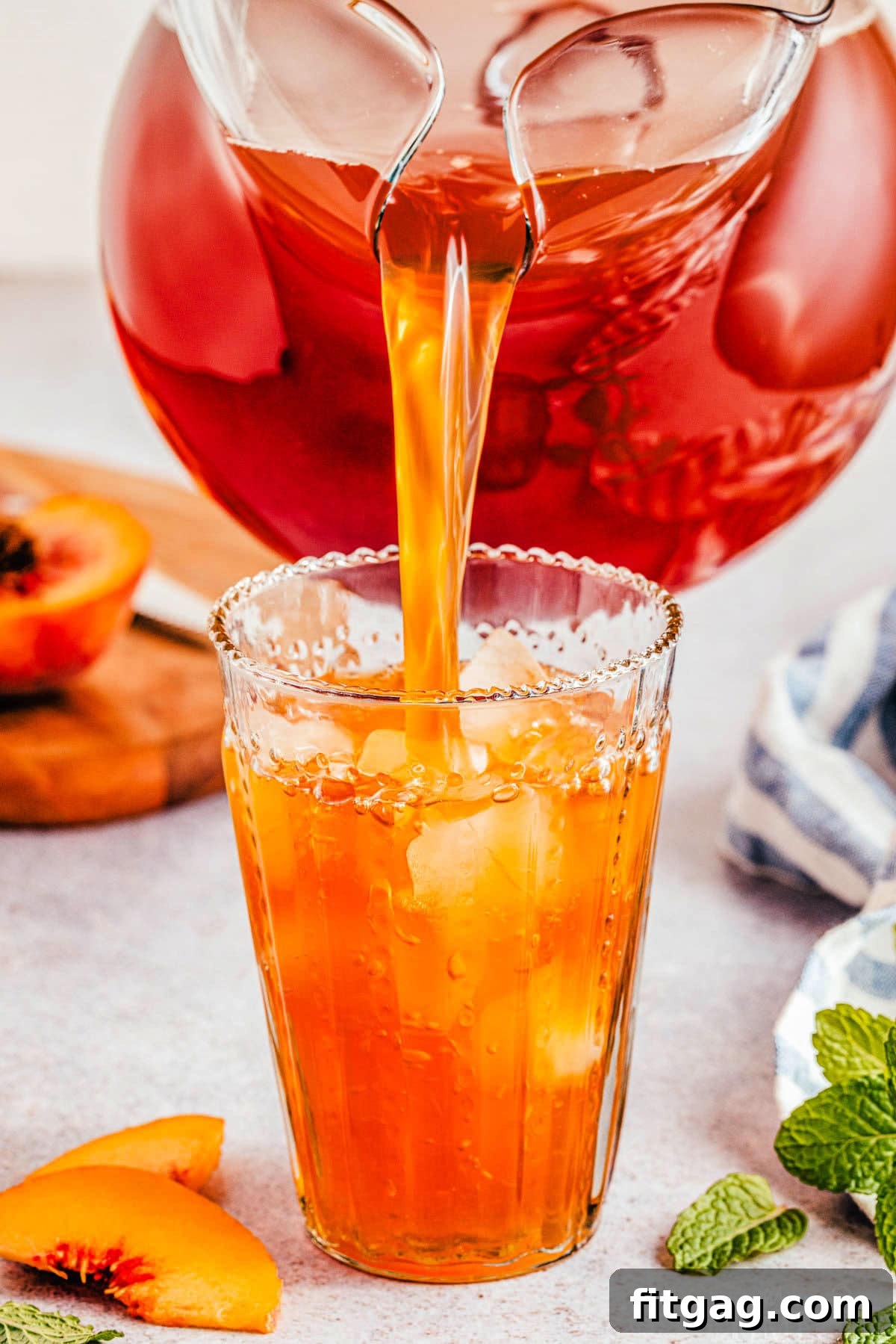Sun-Kissed Peach Brew 4 Large pitcher of peach tea being poured into a tall glass with ice.
