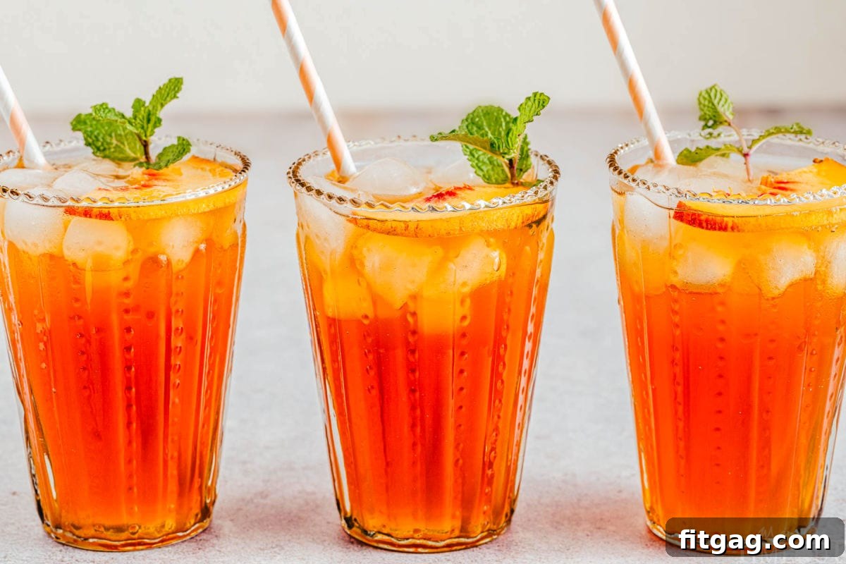Sun-Kissed Peach Brew 7 three glasses of peach iced tea in a line garnished with mint sprigs and slices of peach.