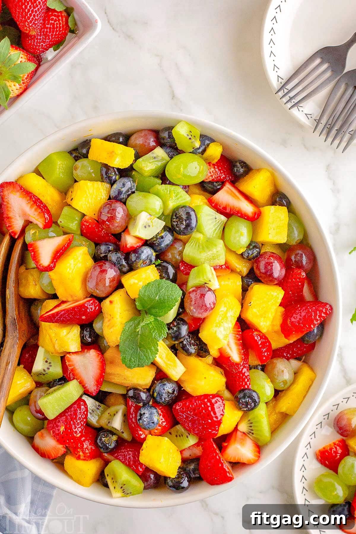 A top down view of a white bowl of fruit salad.