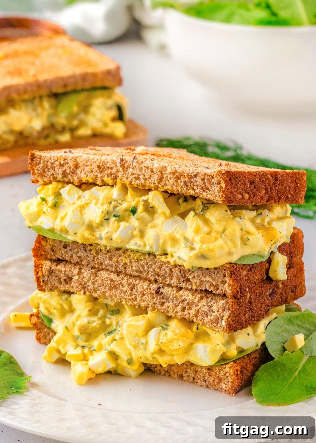 Savory Egg Salad Sensation 2 Two perfectly assembled egg salad sandwiches, stacked on a plate, showcasing the creamy filling and fresh bread.