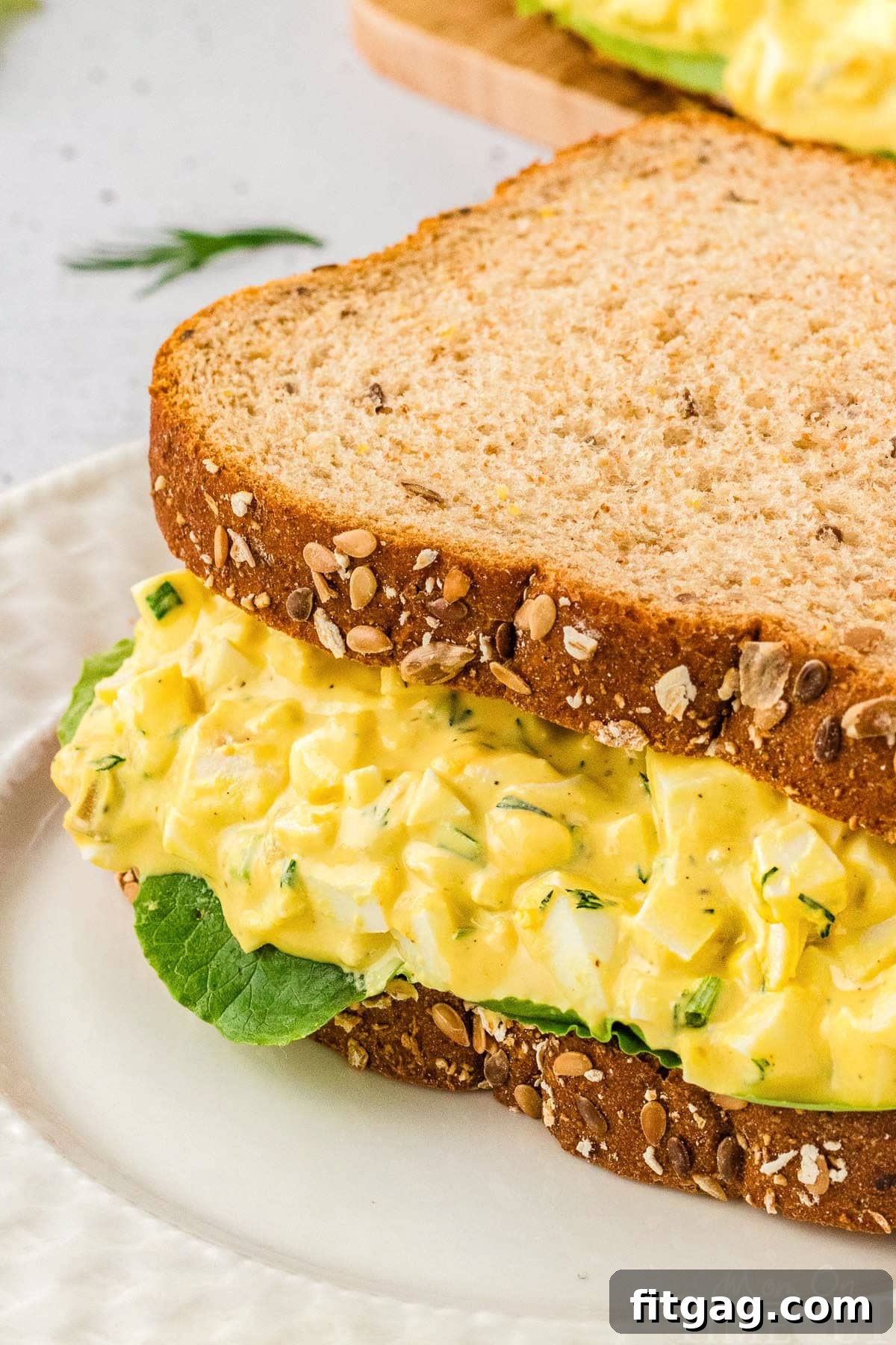 Savory Egg Salad Sensation 5 A close-up view of a thick, delicious egg salad sandwich, highlighting the creamy filling and fresh ingredients.