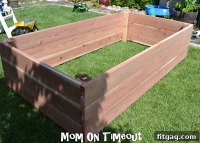 The final long side of the raised planter box is being carefully positioned and screwed into place.